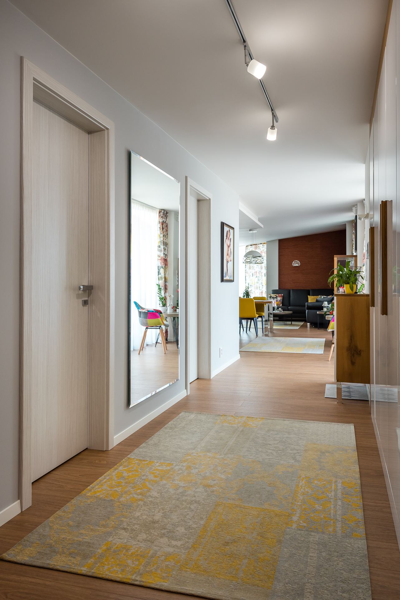 Hallway with wood-look floor and grey-yellow rug leading into the living area of the Hoblina earth-sheltered house in Košice.