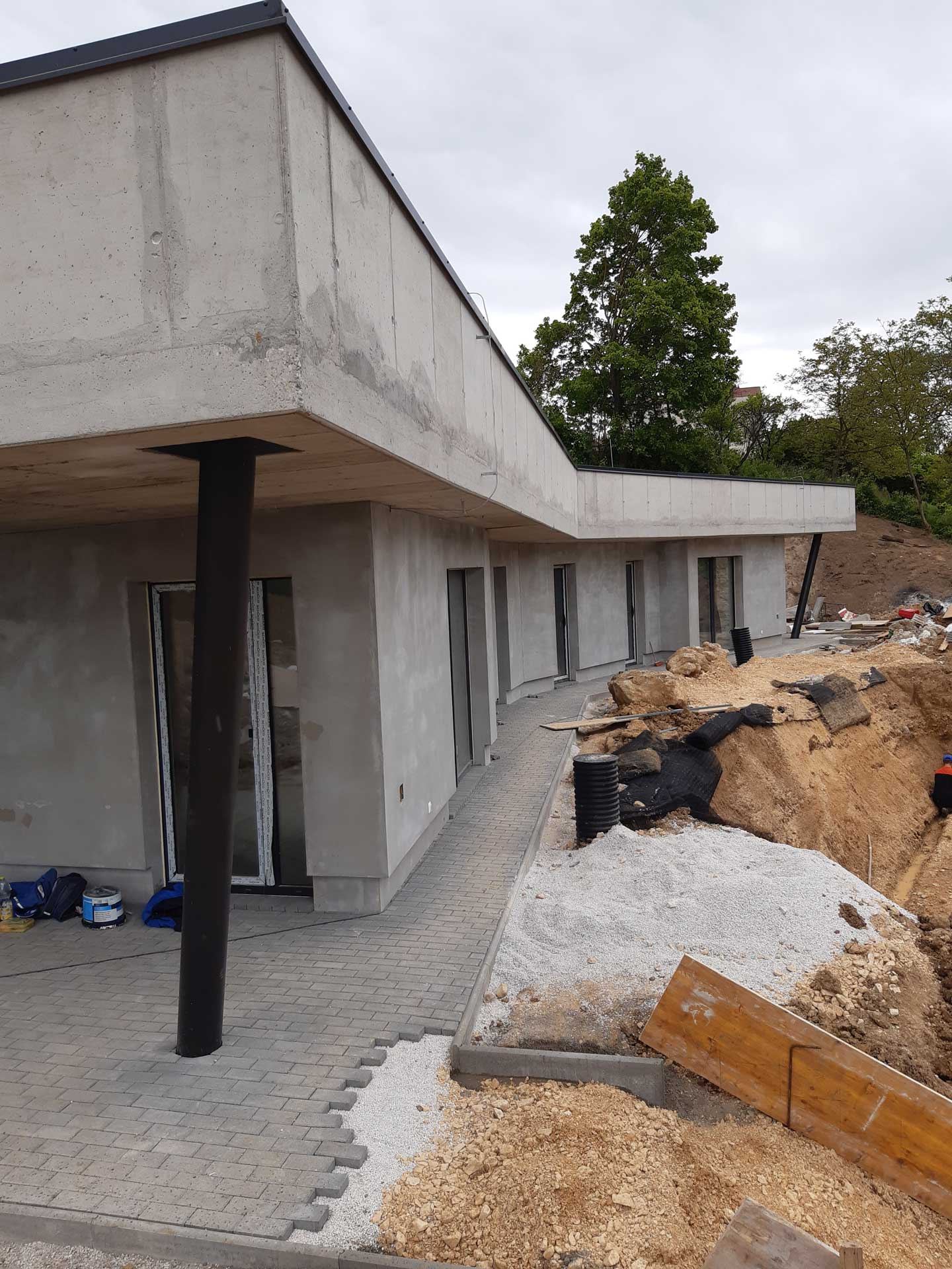 Casa interrata a Trencin in costruzione, facciata vetrata su un sottile pilastro, terrazza accanto a terra scavata e tubi