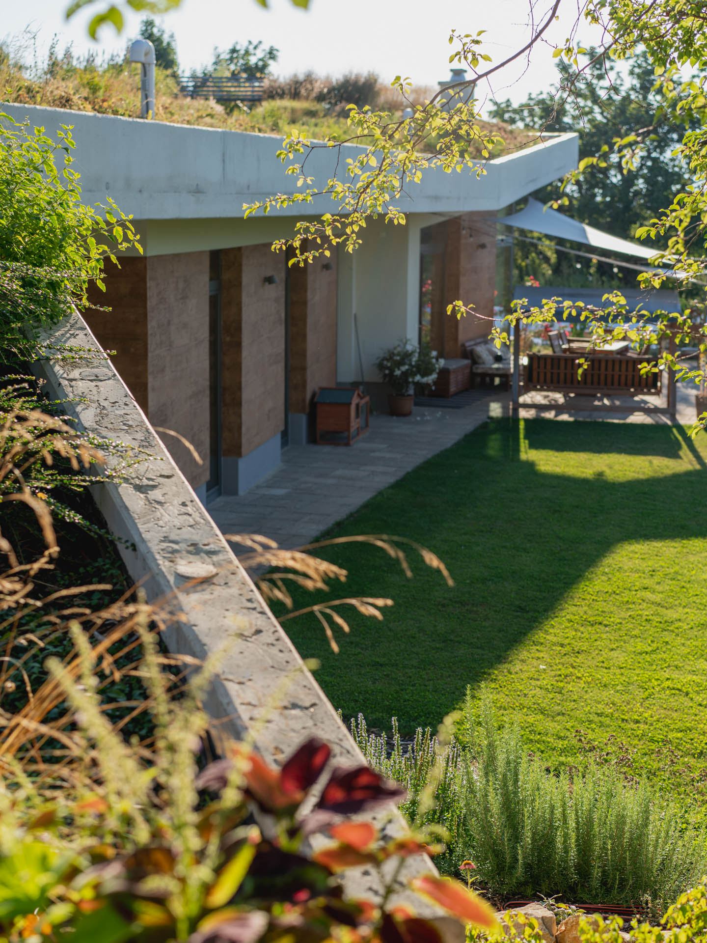 Earth-sheltered house in Nove Mesto nad Vahom, grass roof with concrete overhang above terrace and sunken garden.