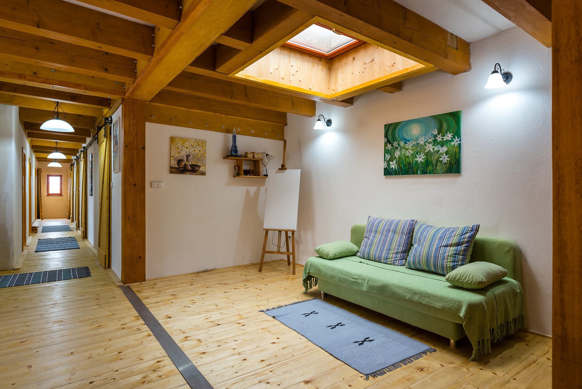 Living room of the Zemplin earth-sheltered house with skylight, wood beams, green sofa and hallway with sliding doors