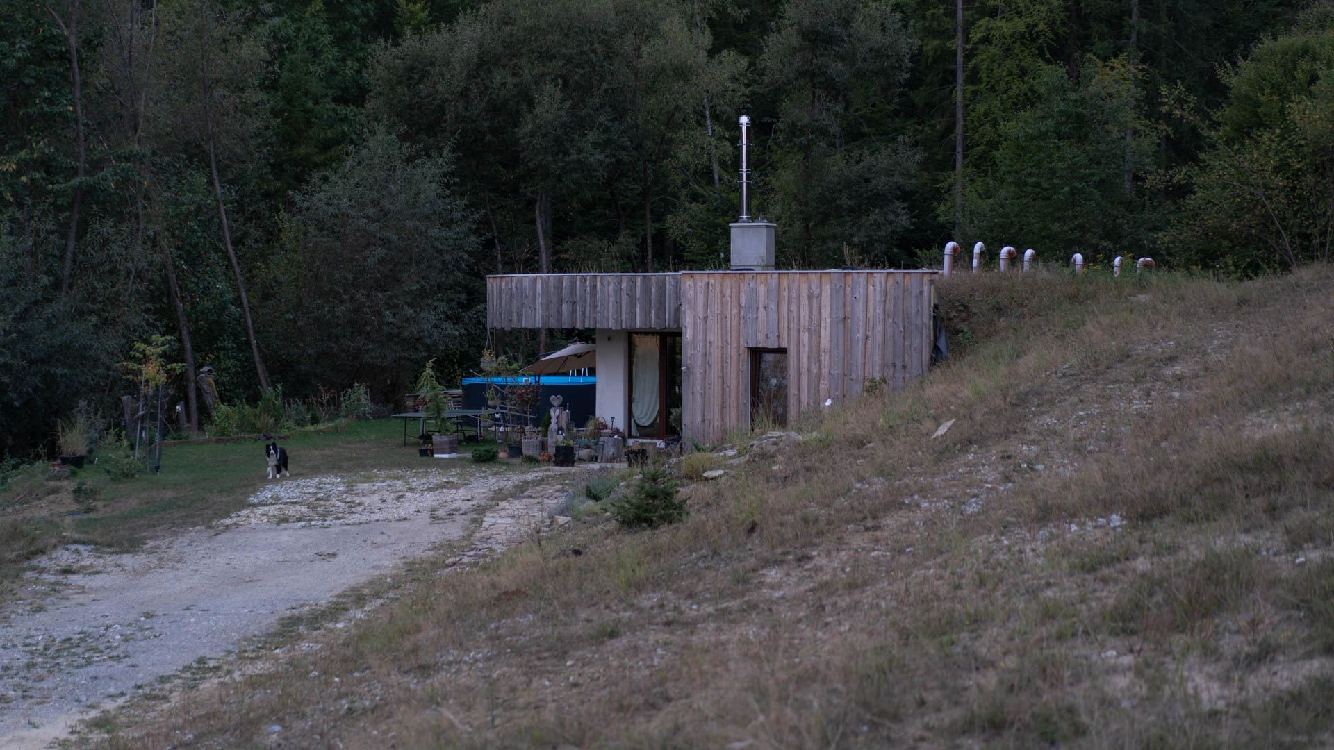 Casa interrata Top Home incassata in un pendio boscoso, terra addossata al muro con tubi di sfiato, cortile con piccola piscina.