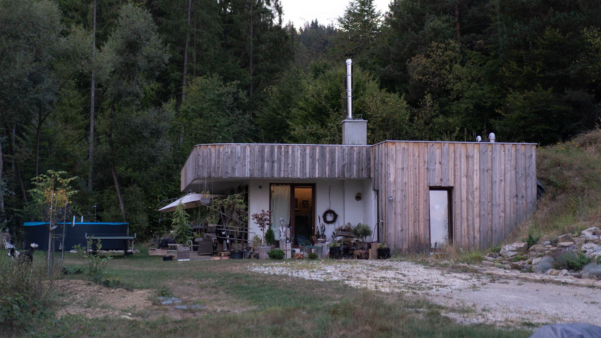 Casa interrata Top Home rivestita in legno addossata a un pendio boscoso, con terrazza, piscina e ping pong in giardino