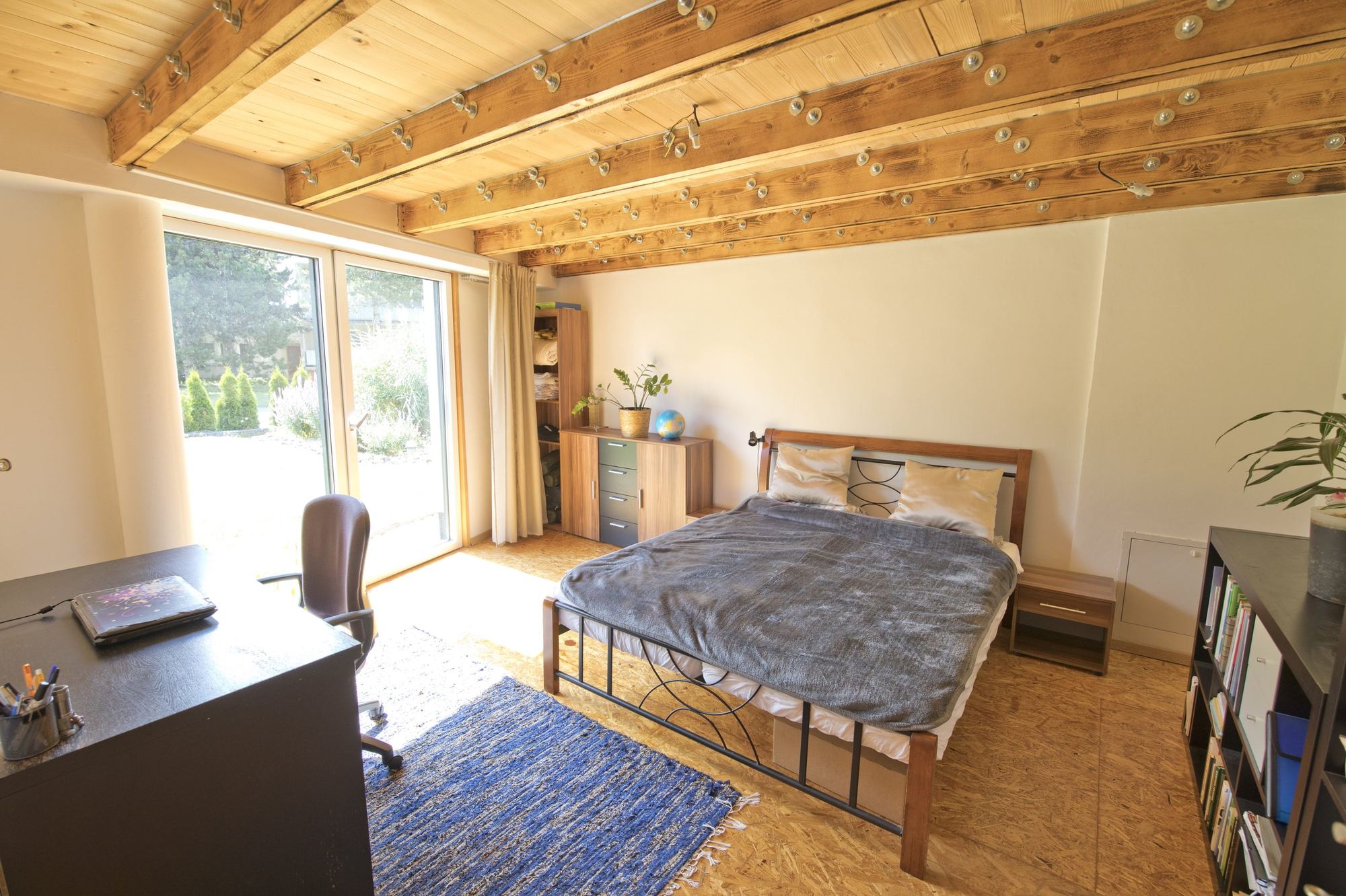 Bedroom of the earth-sheltered house in Rohožník, with a glazed door onto the roof garden beside the bed