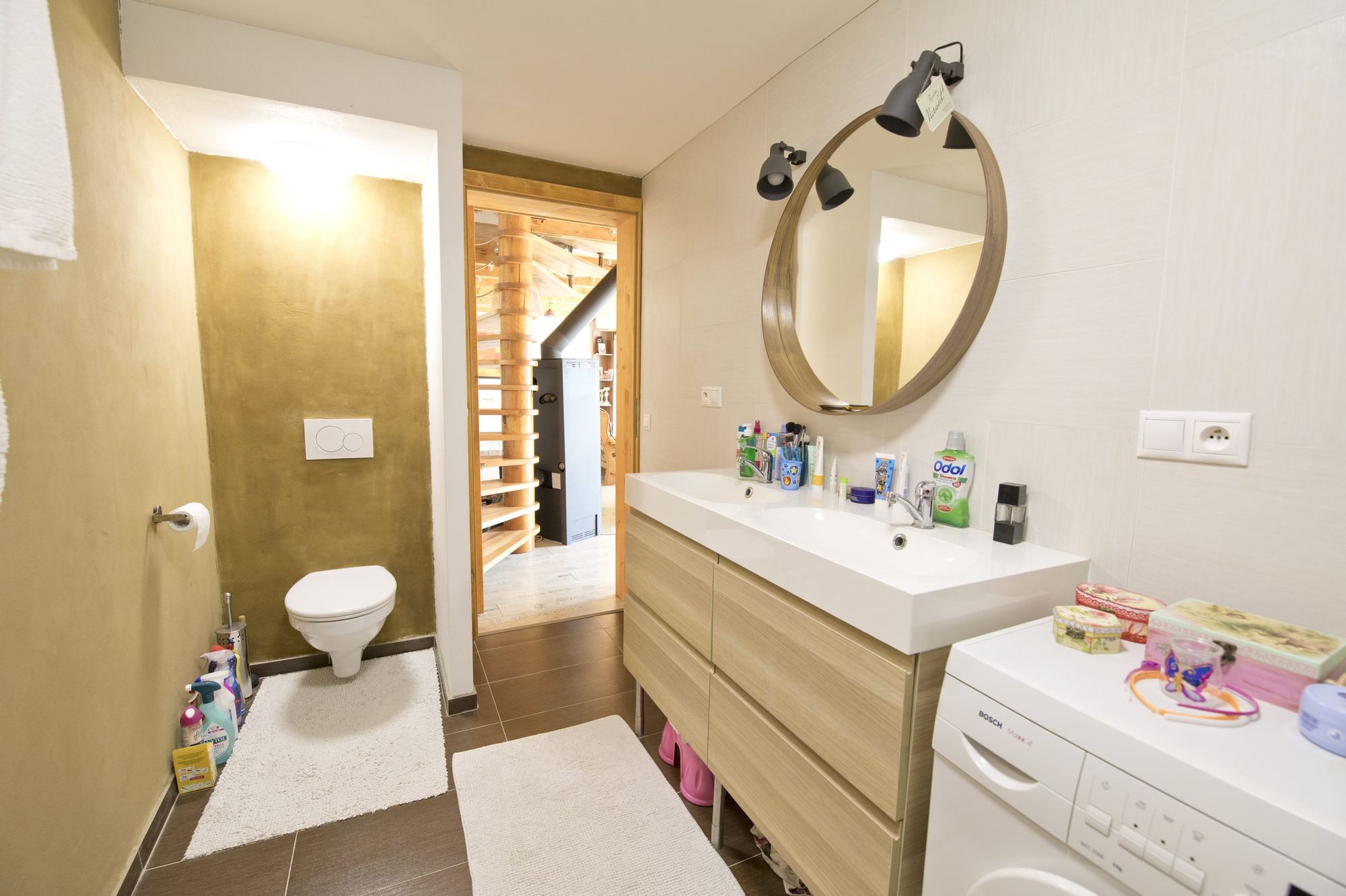Bathroom in the earth-sheltered house in Rohoznik, with ochre wall toilet alcove, wood vanity and washing machine