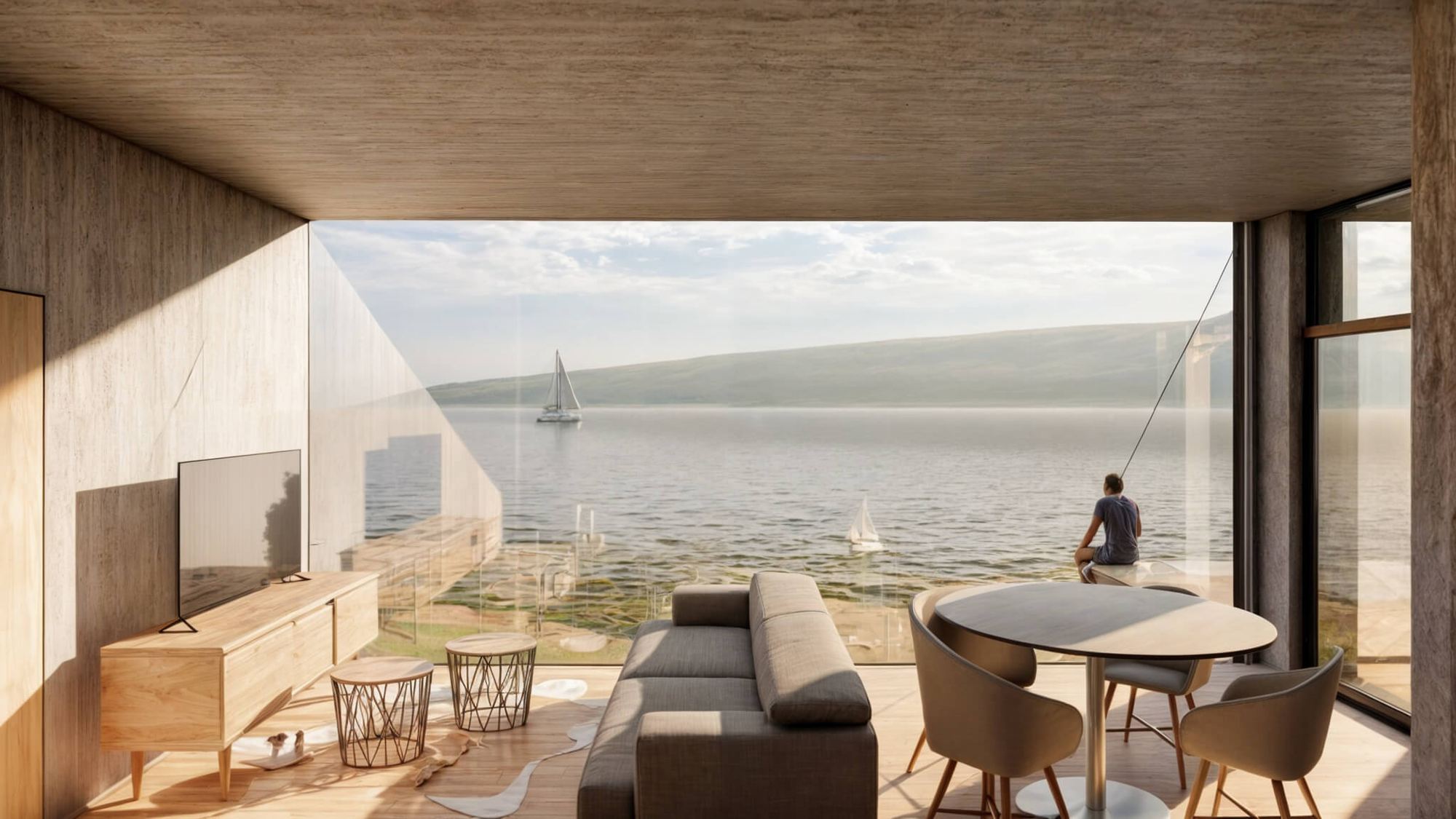Living room of the Bytča earth-sheltered house, concrete ceiling and glazed corner facing the lake, person seated by the window.