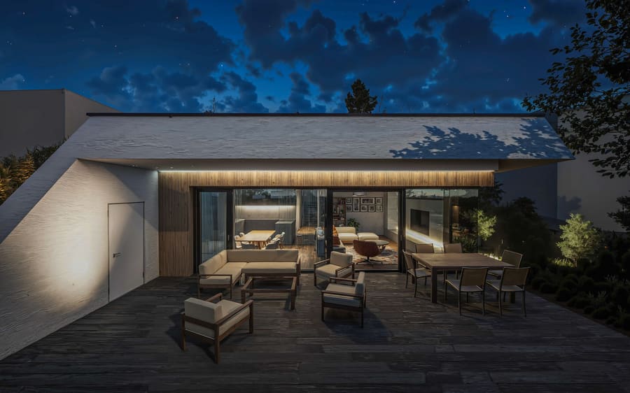 Vista notturna di una casa interrata a Bratislava, facciata vetrata illuminata con tavolo e isola cucina, terrazza con divani